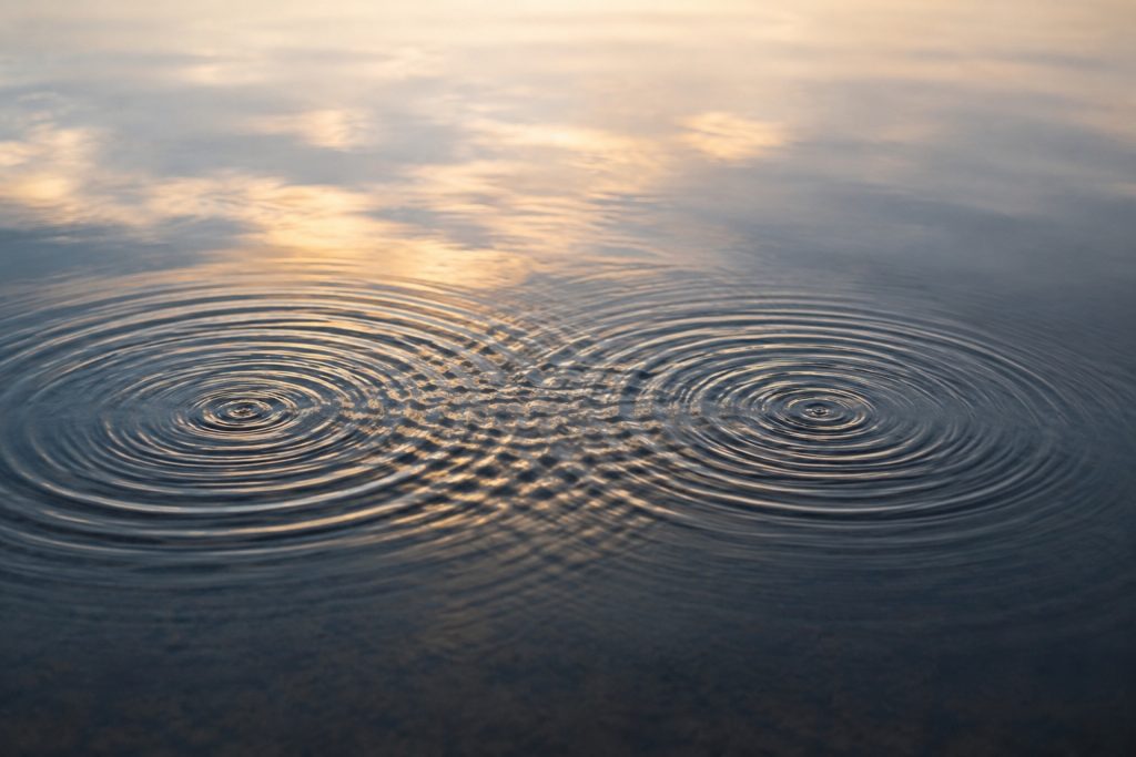 Zwei sich überschneidende Wellenkreise auf ruhigem Wasser im Abendlicht, Symbolbild für die ausgleichende Wirkung von EMDR in Stein bei Nürnberg